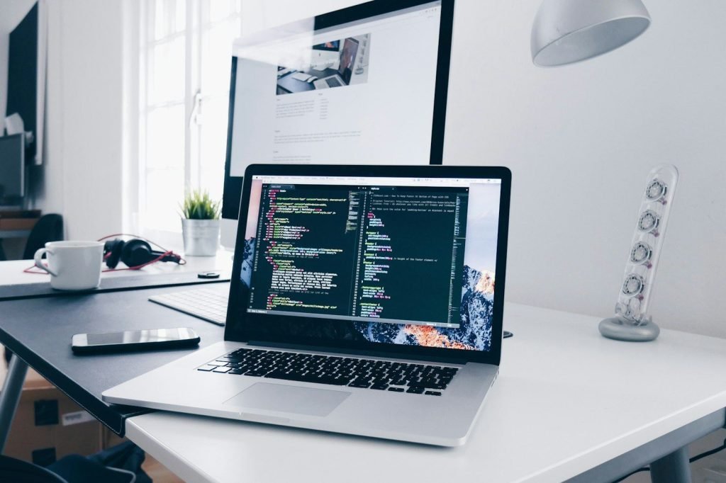 Laptop on a desk showing code during a website build